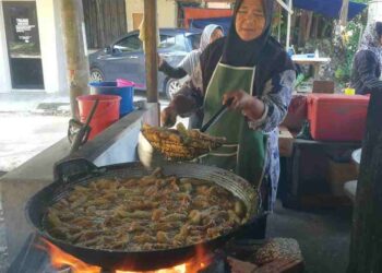 ROKIAH Saleh menggoreng pisang menggunakan kayu api di gerainya di Kampung Tengah, Chukai, Kemaman. – UTUSAN/NIK NUR IZZATUL HAZWANI NIK ADNAN