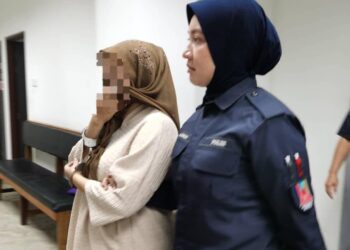TERTUDUH (kiri) diiringi polis semasa hadir untuk perbicaraan di Mahkamah Majistret, Kota Bharu, Kelantan hari ini-UTUSAN/ROSALWANI CHE SOH