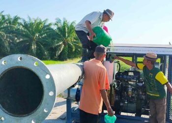 MUHAMMAD Arshad (kanan) dan pesawah mengisi minyak pada pam bergerak yang mengepam air dari parit berdekatan ke sawah mereka di Parit Haji Ali 1, Alor Pongsu dekat Bagan Serai. – UTUSAN/WAT KAMAL ABAS