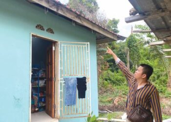 MOHAMAD Khairul Adlan Husin menunjukkan kesan banjir yang menenggelamkan keseluruhan rumahnya ketika banjir paling buruk melanda kampung itu dua tahun lalu.