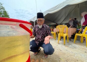 ASMADI Mohamed menunjukkan air telaga tiub yang tidak berkualiti digunakan untuk mencuci tangan sepanjang kenduri diadakan di rumahnya di Kampung Raja Dagang, Pasir Puteh, Kelantan. 
– MINGGUAN/TOREK SULONG