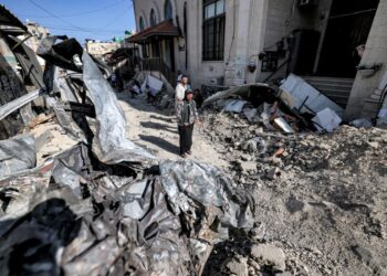 PENDUDUK Palestin melihat runtuhan bangunan dan kenderaan yang musnah di luar sebuah masjid di bandar Jenin di Tebing Barat.-AFP