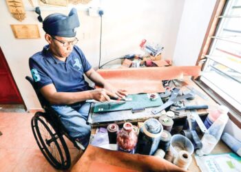 JAAFAR ATHAN memotong kulit lembu untuk dijadikan produk kulit di Felda Tenang, Labis Segamat.