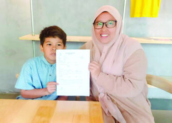 NUR SYAHILAH Iskandar dan Nur Muhammad Adam menunjukkan laporan polis mencari ibu kandung yang dibuat di Cheng, Melaka. 
– UTUSAN/AMRAN MULUP