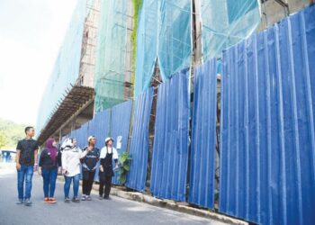 PENIAGA berhampiran tapak pembinaan Menara K-Parc di Kampung Padang Bakau, Kangar, Perlis meninjau pelaksanaan projek berkenaan yang menimbulkan kegusaran mereka khususnya membabitkan faktor keselamatan. - UTUSAN/IZLIZAN OTHMAN