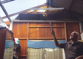 KAMARUDDIN Jusoh menunjukkan sebahagian atap rumahnya yang diterbangkan ribut di Kampung Telaga Daing, Sebarang Takir, Kuala Nerus, hari ini.- UTUSAN/TENGKU DANISH BAHRI TENGKU YUSOFF