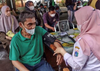 PETUGAS kesihatan menjalankan pemeriksaan sebelum menyuntik vaksin kepada penduduk di sebuah pusat kesihatan di Jakarta.-AFP