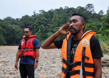 SHAHRIZAL Sariman (kanan) melaungkan azan sebagai ikhtiar mencari adiknya, Muhammad Fikri Saliman dan Putri Nor Fatin Karim di Jeram Mawar, Air Putih, Kemaman, petang tadi. - UTUSAN/PUQTRA HAIRRY ROSLI