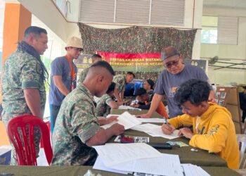 KAMAL Pardi (kanan) melihat seorang belia Orang Asli mengisi borang untuk menyertai Askar Wataniah di Pos Brooke, Gua Musang, Kelantan.UTUSAN/AIMUNI TUAN LAH