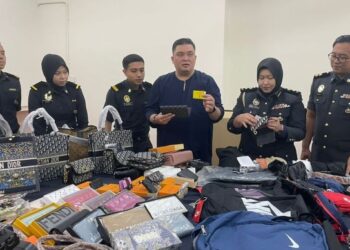 ARIFFIN Samsudin (tiga dari kanan) menunjukkan antara barang disyaki tiruan yang dirampas dalam serbuan di Jalan Petaling, Kuala Lumpur.