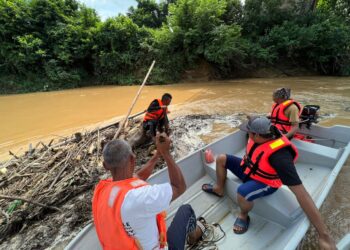 ANGGOTA pasukan penyelamat yang menyertai operasi SAR mengalihkan longgokan kayu bagi mencari mangsa terakhir tragedi kepala air di Jeram Mawar, Air Putih, Kemaman, hari ini. - UTUSAN/NIK NUR IZZATUL HAZWANI NIK ADNAN