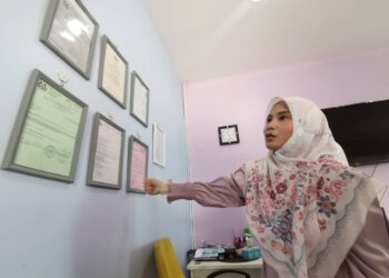 TINA Tajuddin menunjukkan sijil-sijil kelayakan untuk sebuah taska beroperasi dalam sidang akhbar di Ipoh hari ini. - UTUSAN