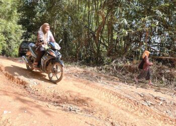 MASYARAKAT Orang Asli mengukir senyuman apabila Jakoa melaksanakan kerja-kerja menaik taraf atau penggredan jalan masuk ke tiga buah pos penempatan mereka di Gua Musang, Kelantan. - UTUSAN/AIMUNI TUAN LAH