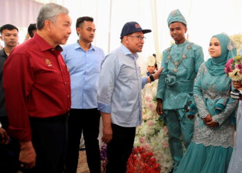 PERDANA Menteri, Datuk Seri Anwar Ibrahim  diiringi Ahmad Zahid Hamidi (kiri) menyantuni pengantin baru di Program Sentuhan Kasih Desa Kelantan di Gua Musang Kelantan.-UTUSAN/KAMARUL BISMI KAMARUZAMAN