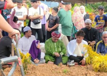 MUHAMAD Huzaifah (duduk, dua dari kanan) sebak ketika majlis pengebumian bapa dan adiknya di dalam satu liang lahad di Tanah Perkuburan Islam Kampung Kerinting, Gua Musang, Kelantan. - UTUSAN/AIMUNI TUAN LAH