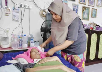 AZIZON Abd. Hamid, mengelap badan anaknya, Azreen yang terlantar dalam keadaan separuh koma sejak empat bulan lalu di kediamannya di Desa An-Nur Panji, Kota Bharu, Kelantan.– utusan/ROSALWANI CHE SOH