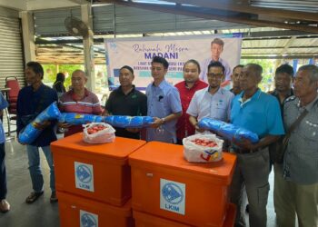MUHAMMAD FAIZ Fadzil (tengah) menyampaikan sumbangan peralatan menangkap ikan kepada 30 nelayan di kawasan Kuantan di Pasar Nelayan LKIM Balok di Kuantan, Pahang. - UTUSAN/DIANA SURYA ABD WAHAB