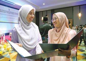 NUR Alia Maisarah Abdullah (kanan) dan Khairunnisa Che Roslan (kiri) menyemak keputusan permohonan  melanjutkan pengajian ke IPTA di Kangar, Perlis, semalam. – UTUSAN/IZLIZAN OTHMAN