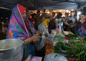 PENIAGA memperagakan pakaian tradisional ketika berniaga di Payang Walk, Kuala Terengganu. - UTUSAN/KAMALIZA KAMARUDDIN