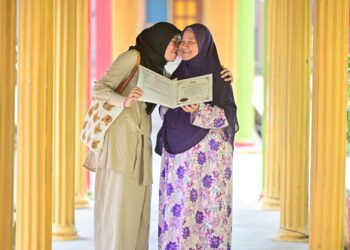 AQILAH Talib (kiri) bersama ibunya, Mariam Chik menunjukkan slip keputusan STPM yang diumumkan di SMK Sultan Sulaiman, Kuala Terengganu. - UTUSAN/PUQTRA HAIRRY ROSLI