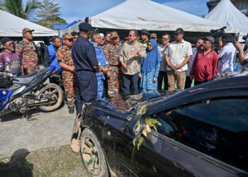 Ahmad Samsuri Mokhtar (tengah) diberi penerangan tentang kejadian kepala air di Jeram Mawar, Air Putih, Terengganu yang menghanyutkan 10 mangsa Sabtu lalu. - UTUSAN/PUQTRA HAIRRY