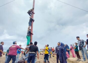 PASANGAN pengantin menyaksikan peserta memanjat tiang licin pada majlis perkahwinan mereka di Sungai Manik dekat Pasir Salak baru-baru ini. - UTUSAN/AIN SAFRE BIDIN