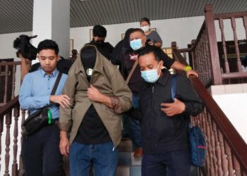 TERTUDUH diiringi pegawai SPRM selepas Mahkamah Sesyen, Ayer Keroh, Melaka menjatuhkan denda RM200,000 kerana menggunakan dokumen palsu. - UTUSAN/MUHAMMAD SHAHIZAM TAZALI