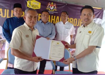 HAMEED MYTHEEN Kunju Basher menyaksikan penyerahan dokumen antara Pengarah Jabatan Kerja Raya (JKR) negeri, Datuk Ir. Ismail Abd. Rahman kepada seorang kakitangan JKR di Tangga Batu, Melaka. - UTUSAN/AMRAN MULUP