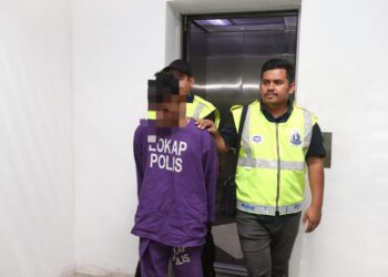 TERTUDUH diiringi polis semasa menghadiri perbicaraan di Mahkamah Sesyen, Kota Bharu, Kelantan hari ini-UTUSAN/ROSALWANI CHE SOH.