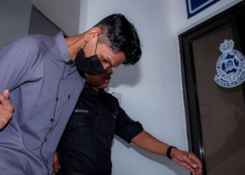 TERTUDUH diiring keluar anggota polis selepas Mahkamah Sesyen, Ayer Keroh, Melaka menjatuhkan menjalani khidmat masyarakat bagi tempoh 240 jam dalam masa dua tahun dan bon berkelakuan baik selama dua tahun dengan penjamin, berserta jaminan sebanyak RM7,000 untuk tiga tahun. - UTUSAN/SYAFEEQ AHMAD
