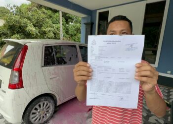 CHE Mohd. Intizan menunjukkan laporan polis selepas keretanya disimbah cecair merah jambu di Kampung Pangkalan Datu, Sering di Kota Bharu, Kelantan kelmarin.UTUSAN/ROHANA MOHD. NAWI