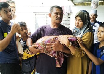 ZULHILMI Ismail Yahya (kiri) tidak dapat menahan sebak ketika jenazah anaknya didukung bapanya, Yahya Mohd Nor ketika ditemui dikediamannya di Kampung Semat Jal, Tumpat, Kelantan-UTUSAN/ROHANA ISMAIL