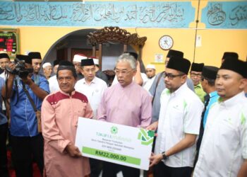 AL-SULTAN Abdullah Ri’ayatuddin Al-Mustafa Billah Shah (tengah) menyampaikan replika cek bayaran tuntutan Skim Takaful Pelajar Sekolah Malaysia kepada Eiyi Johari, 60, (depan, kiri) di Masjid Ubbudiah di Kuantan, Pahang. - FOTO/SHAIKH AHMAD RAZIF