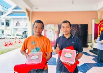 MOHD. Azli Deraman (kiri) dan adik kembarnya, Mohd. Azlan antara penerima sumbangan daging lembu daripada McDonald's Malaysia di Kuala Terengganu, hari ini. - UTUSAN/KAMALIZA KAMARUDDIN