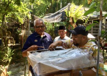 MAHFUZ Omar (kiri) melihat salah satu sarang madu kelulut di Galeri Madu Kelulut Bukit di Kampung Bukit Bayas, Kuala Terengganu, hari ini. - UTUSAN/TENGKU DANISH BAHRI TENGKU YUSOFF