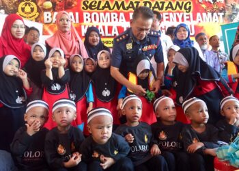 HASSAN 'As'ari Omar memakaikan jaket keselamatan kepada salah seorang anak yatim pada  Program Kesedaran Kebakaran BSN di Kuala Terengganu, petang tadi. - UTUSAN/TENGKU DANISH BAHRI TENGKU YUSOFF