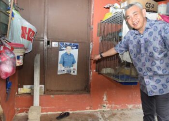 MOHD. Sobri Alwi menunjukkan poster kempennya ketika bertanding dalam PRU14 masih tertampal di salah sebuah rumah seorang penduduk di Kampung Bukit Kecil, Kuala Terengganu, hari ini. - UTUSAN/KAMALIZA KAMARUDDIN