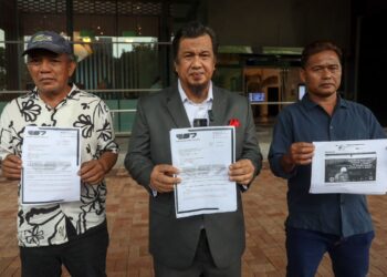 ZULKARNAIN Mahdar (tengah) menunjukkan laporan yang dibuat berhubung fitnah ke atas Ketua Menteri Sabah di SKMM, Cyberjaya. - UTUSAN/KAMARIAH KHALIDI