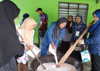 Dr. ROHAFIZ Sabar (kanan) dan masyarakat bersama-sama mengacau bubur asyura di Perik, Kuala Nerang, baru-baru ini.