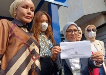 MELISSA Anggraini (tengah) menunjukkan laporan polis berhubung gangguan seksual yang dibuat anak guamnya di Balai Polis Metro Jaya.-AGENSI  