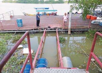 PENDUDUK menunjukkan keadaan titi yang menghubungkan pelantar dan jeti yang patah di Dataran Udang Galah di Teluk Intan. – UTUSAN/AIN SAFRE BIDIN
