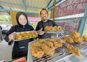 HARIZ Mohd. Aswani (kanan) bersama isterinya menunjukkan sebahagian ayam goreng RM1 di warungnya di Kampung Raja Dagang, Semerak, Pasir Puteh, Kelantan. - UTUSAN/TOREK SULONG