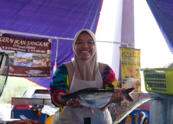 NOOR Zarifah Mohamad Basri memegang ikan patin yang dijualnya di Pasar Besar Jerantut di Jerantut, Pahang. – UTUSAN/NORHAFIZAN ZULKIFLI