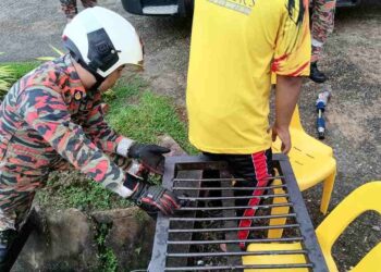 ANGGOTA bomba Limbang berusaha mengeluarkan kaki seorang pelajar yang tersepit pada besi penutup longkang.