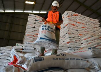 SEORANG pekerja menyusun guni beras yang diimport dari Thailand di Gudang Bulog di Lambaro, wilayah Aceh. - AFP
