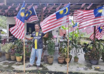 MOHD. Salim Jaafar memasang Jalur Gemilang di kedai makannya di Durian Tunggal, Melaka sebagai simbolik 66 tahun kemerdekaan Malaysia. – UTUSAN/MUHAMMAD SHAHIZAM TAZALI