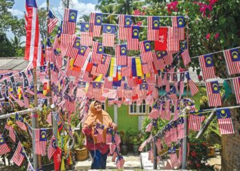 SEORANG warga peneroka, Rahmah Mohd. Nor menghiasi pekarangan rumahnya dengan Jalur Gemilang di Felda Tersat, Hulu Terengganu, Terengganu bagi menunjukkan semangat patriotik terhadap negara sempena sambutan Hari Kebangsaan Ke-66 pada 31 Ogos ini. - UTUSAN/PUQTRA HAIRRY