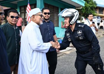 ABDUL Hadi Awang (dua dari kiri) bersalaman bersama Ketua Polis Terengganu, Datuk Mazli Mazlan selepas selesai mengundi di Pusat Pengundian SK Rusila, Marang, hari ini. - UTUSAN/PUQTRA HAIRRY ROSLI