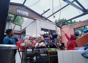 NORAINI Md Zin dan anaknya, Mohd. Ashraf Mohd. Shukri melihat bahagian bumbung premis kedai makan mereka yang rosak selepas diterbangkan angin di Kuala Sala, Alor Setar, Kedah awal pagi semalam.