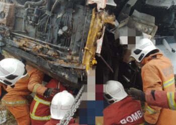 ANGGOTA bomba berusaha memotong salah satu pintu lori tangki minyak bagi mengeluarkan mangsa yang tersepit.